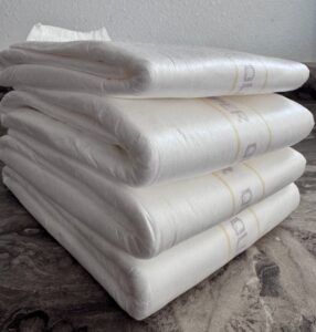 stack of four Seni Super Quatro adult diapers showing thickness and bulk